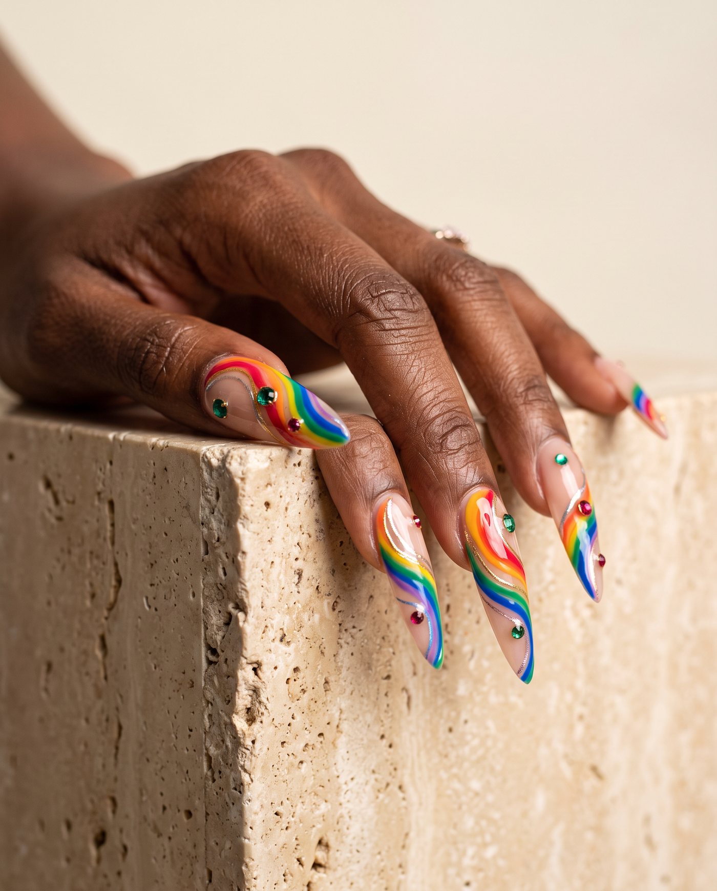 Extra-long stiletto nails with abstract rainbow swirls and set gemstones